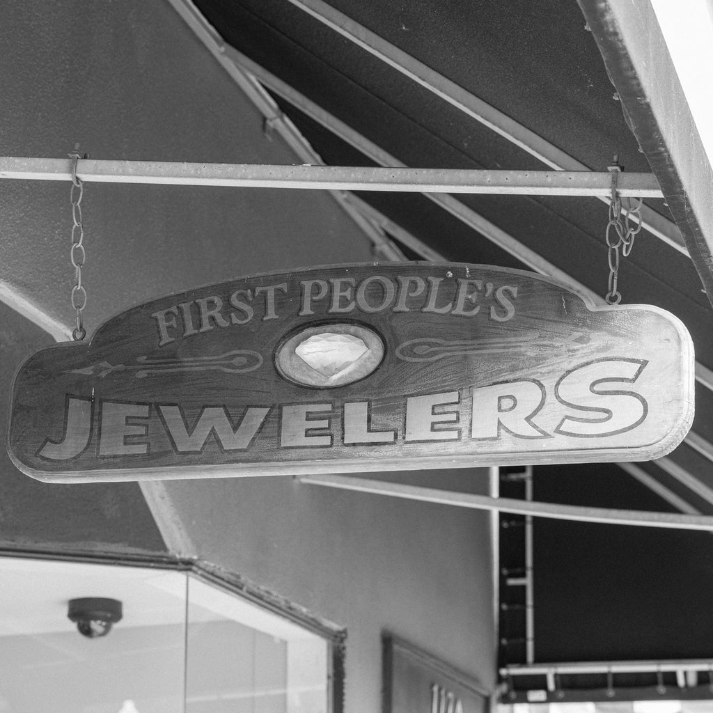 Sign for 'First People's Jewelers' hanging from an awning.